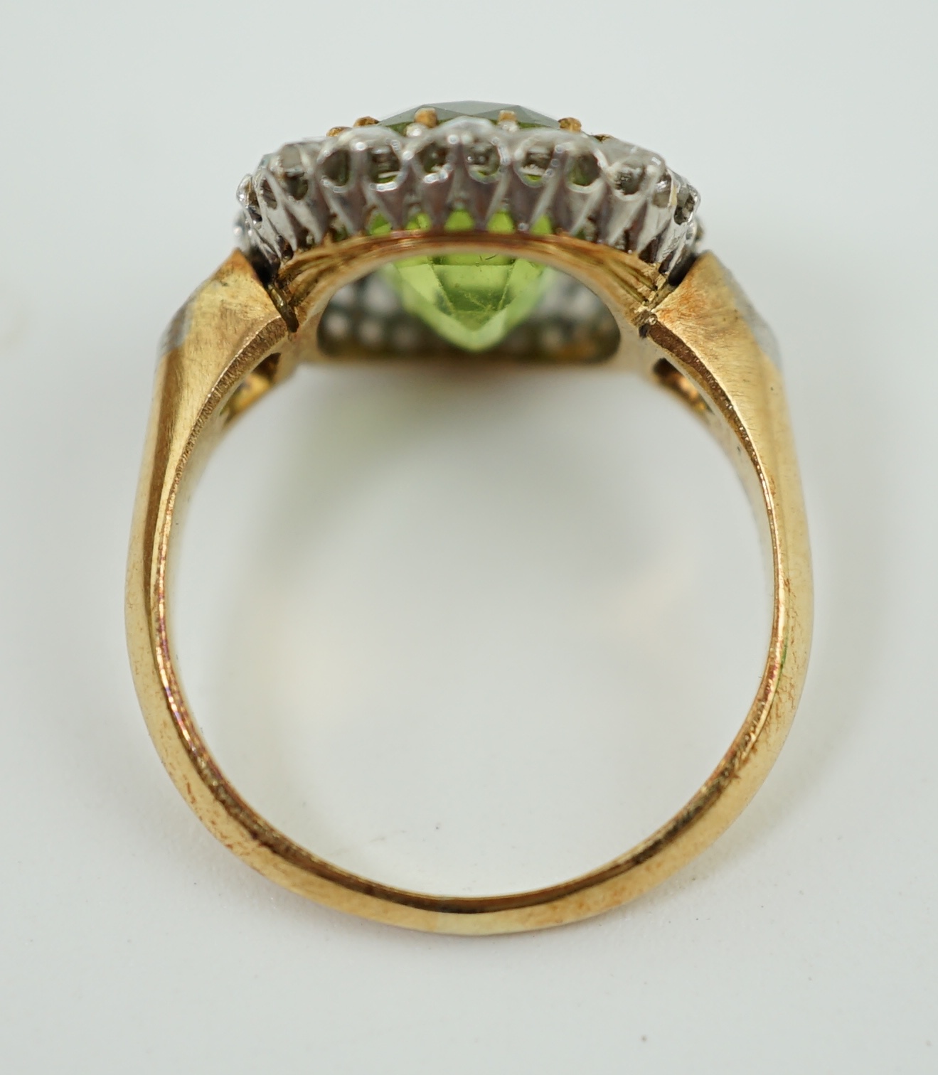 An early 20th century gold, peridot and diamond set oval cluster ring